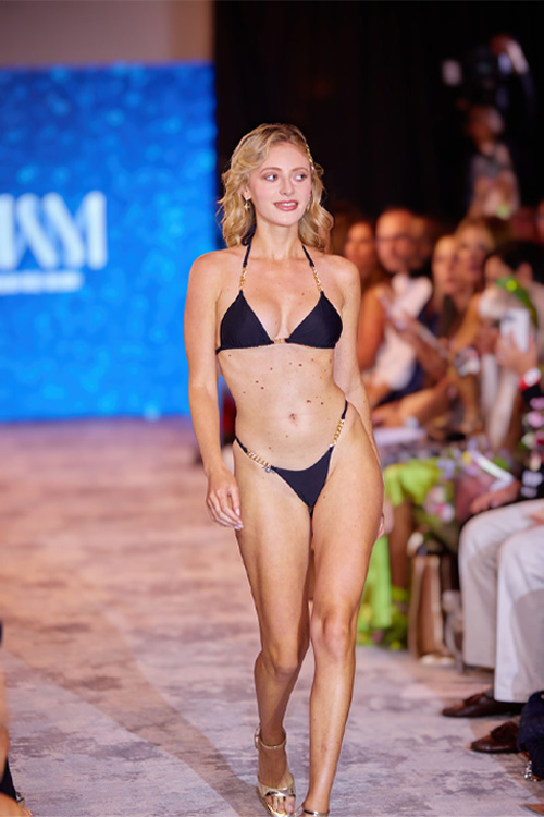 model wearing a black triangle bikini with gold metal accents